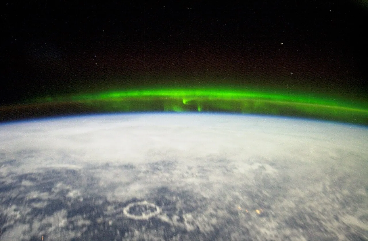 Green aurora borealis photographed from the International Space Station above Earth at night.