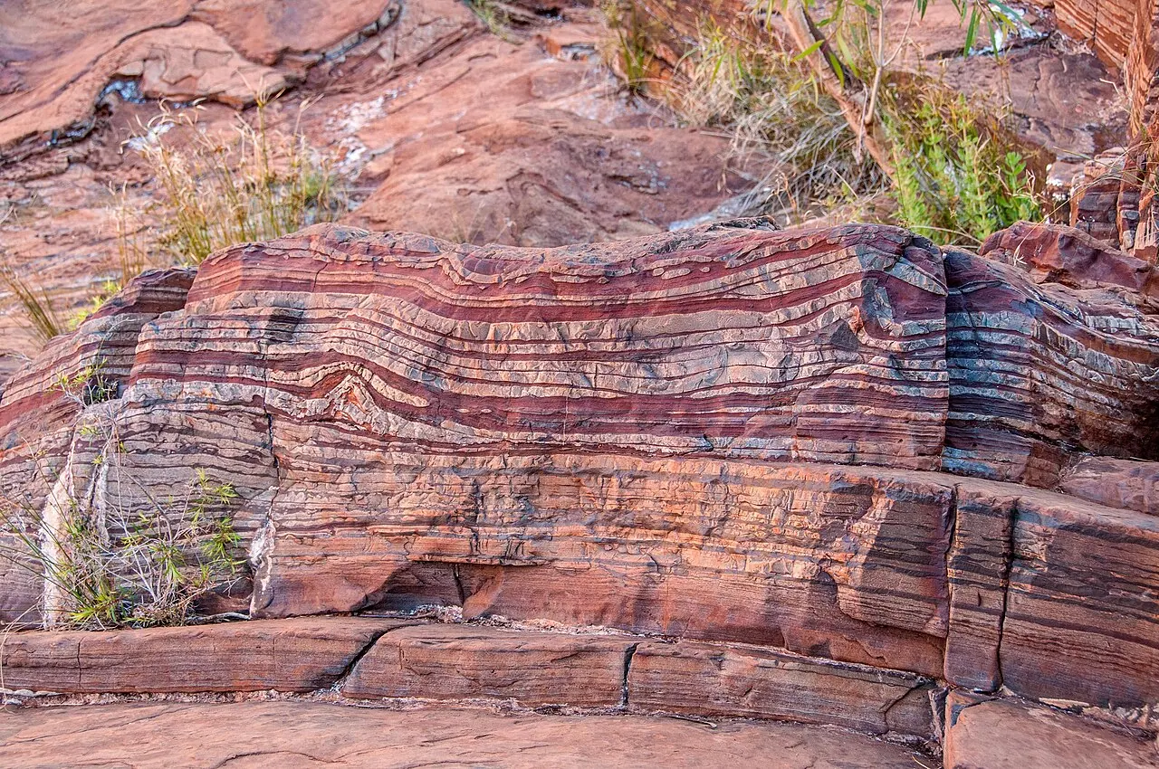 Striped red and dark bands of a banded iron formation, recording the rise of oxygen in Earth's early ocean.